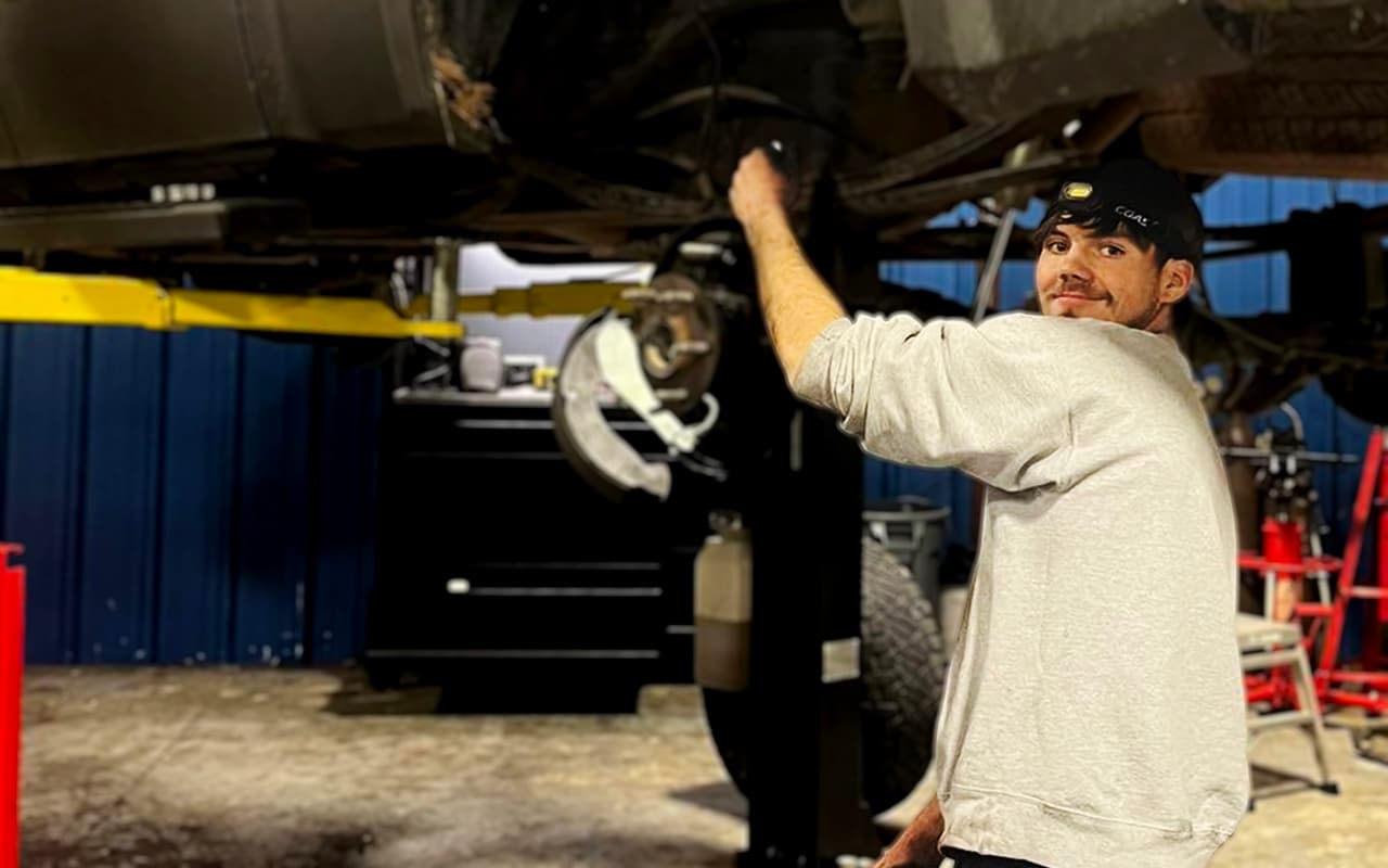 Cayden working under a vehicle on a lift